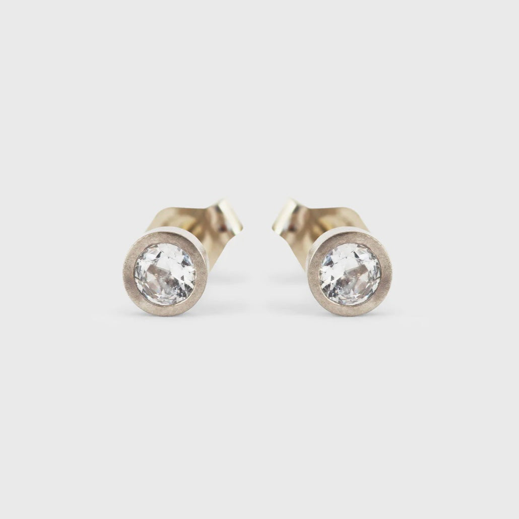 Introducing SAPPHIRE / STUDS, a collection of elegant and timeless earrings that are perfect for any occasion. With their versatile design, they can effortlessly elevate your style from day to night. Don't miss out on adding these stunning pieces to your jewelry collection! Two 3mm Round White Sapphires 14k Yellow Gold 4mm round studs HxW: 14.7mm x 9.5mm